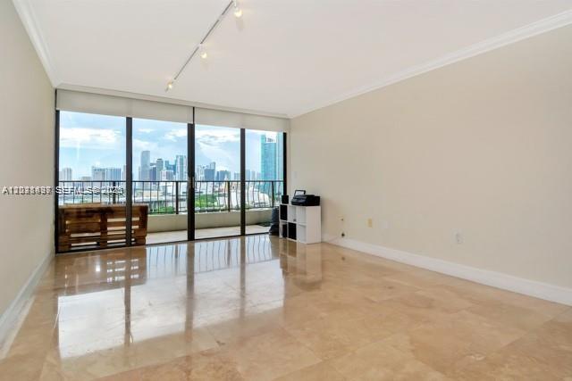 An empty room with beige tile floors and a balcony overlooking a city skyline — 555 NE 15th St # 16H, Miami FL 33132, MIAMI, FL