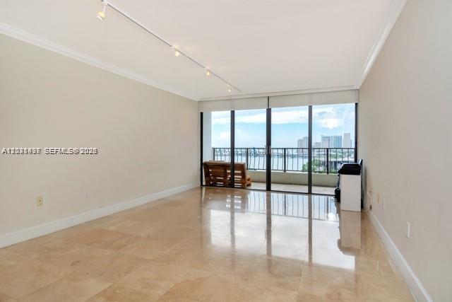 A bright, empty room features light-colored tile floors, track lighting, and a balcony with water views — 555 NE 15th St # 16H, Miami FL 33132, MIAMI, FL