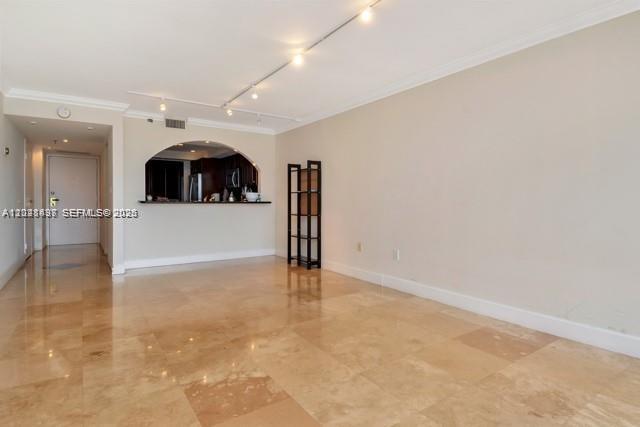 An open living area features light-colored tile flooring, track lighting, and an arched kitchen pass-through — 555 NE 15th St # 16H, Miami FL 33132, MIAMI, FL