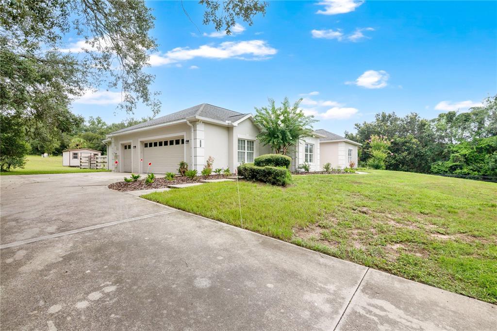 A single-story house with a beige exterior, a two-car garage, and a large grassy yard — 22841 STALLION DRIVE, SORRENTO, FL