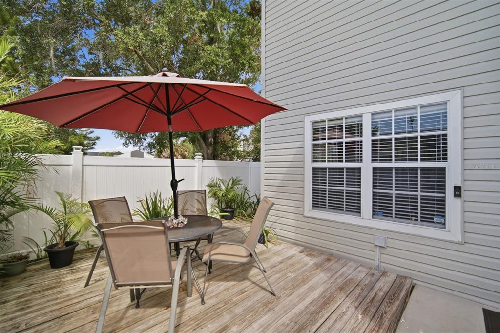 A wooden deck features a patio table with four chairs under a red umbrella — 8350 SAVANNAH TRACE CIRCLE UNIT 305, TAMPA, FL