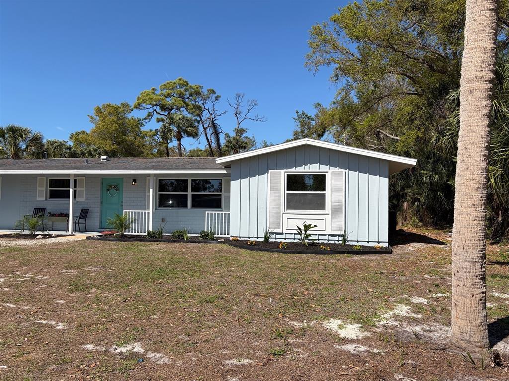 A light blue single-story house features a teal front door and a large front window — 201 PALMETTO ROAD, NOKOMIS, FL