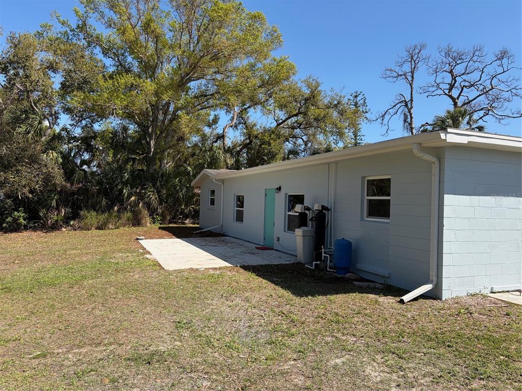 The exterior of a light blue house features a concrete patio and a water filtration system — 201 PALMETTO ROAD, NOKOMIS, FL