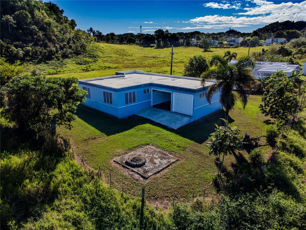 An aerial view shows a blue, single-story house with a flat roof and attached garage — 480 CALLE S. TOSADO, QUEBRADILLAS, PR