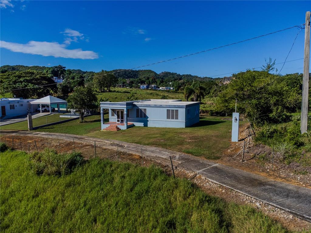 A light blue single-story house sits on a grassy lot with a paved driveway — 480 CALLE S. TOSADO, QUEBRADILLAS, PR