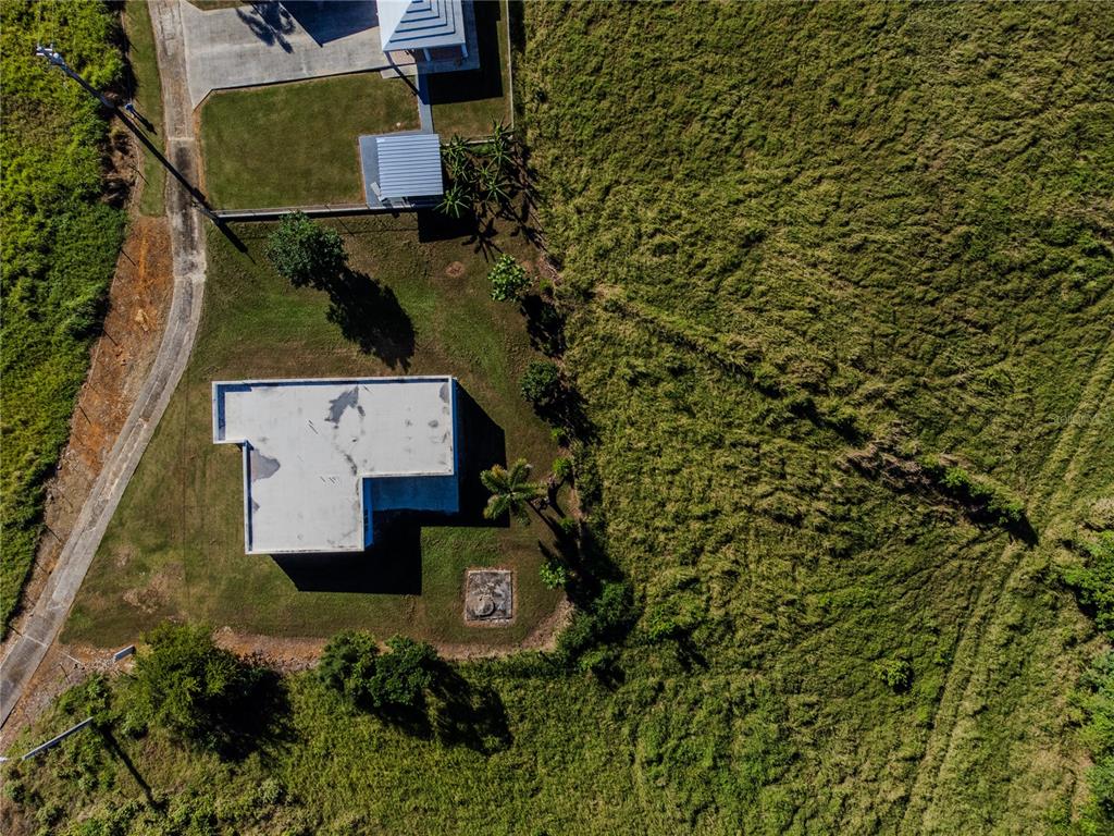 An aerial view shows a house with a flat roof surrounded by grassy fields — 480 CALLE S. TOSADO, QUEBRADILLAS, PR