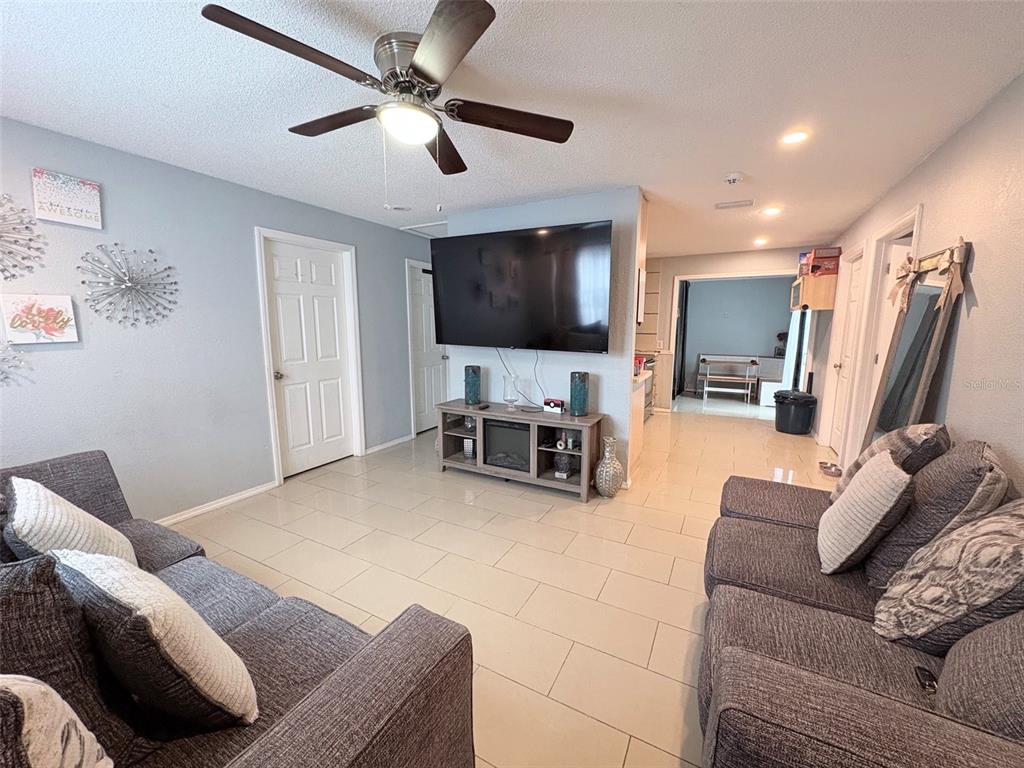 A living room features a large television, a media console, and two grey sofas — 7095 54TH AVENUE N, ST PETERSBURG, FL