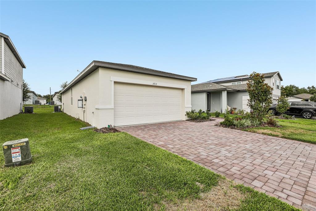 A single-story house with a beige stucco exterior and a paved driveway — 3713 QUEENSLAND COURT, HAINES CITY, FL