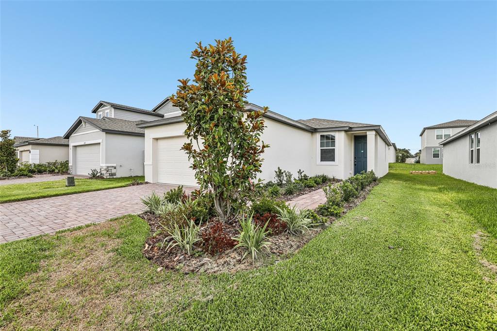 A single-story house with a paved driveway, a small front garden, and a blue door — 3713 QUEENSLAND COURT, HAINES CITY, FL