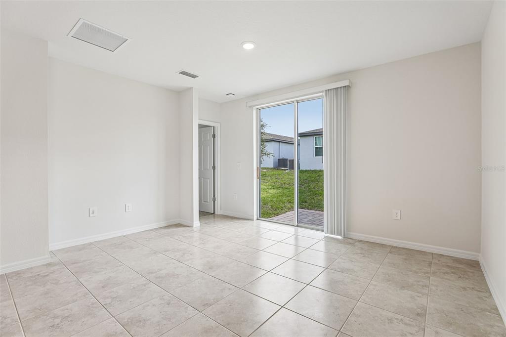 An empty room with light-colored tile flooring, white walls, and a sliding glass door — 3713 QUEENSLAND COURT, HAINES CITY, FL