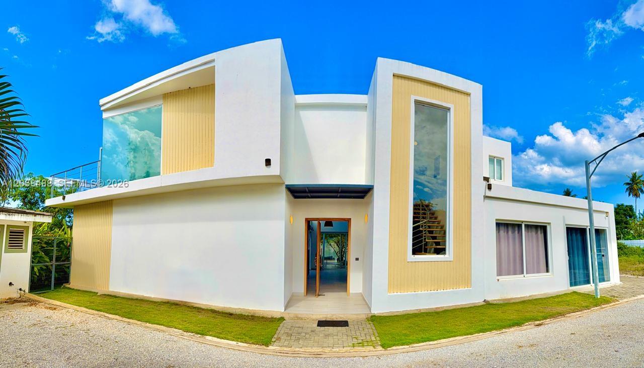 A modern white two-story house features large glass windows and light wood-toned accent panels — 00 CALLE MARIANO VANDERHORST, 3200, FL