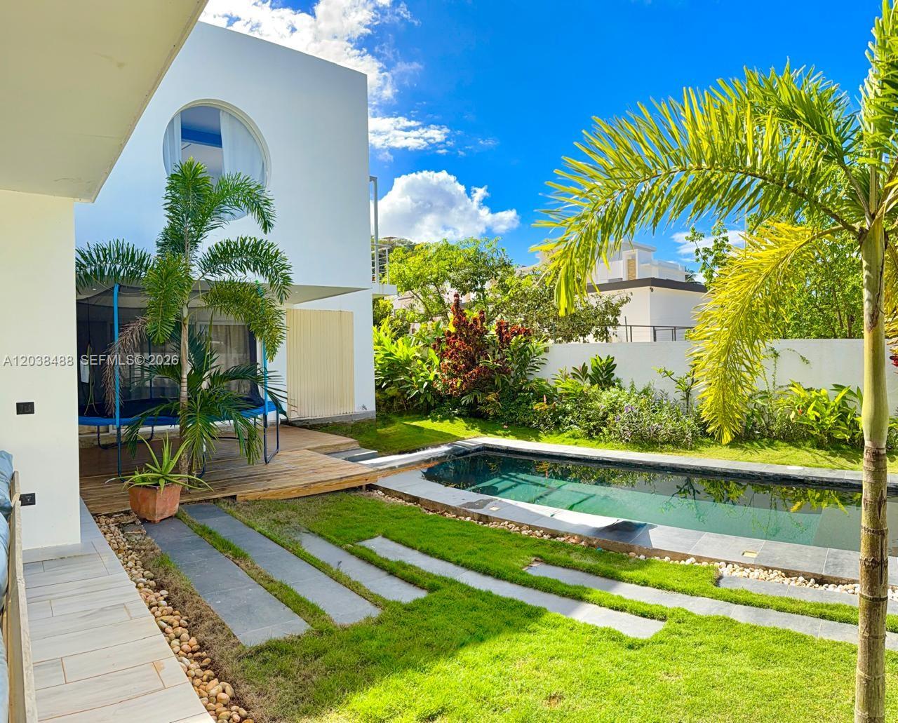 A backyard features a rectangular swimming pool, a wooden deck, a trampoline, and palm trees — 00 CALLE MARIANO VANDERHORST, 3200, FL