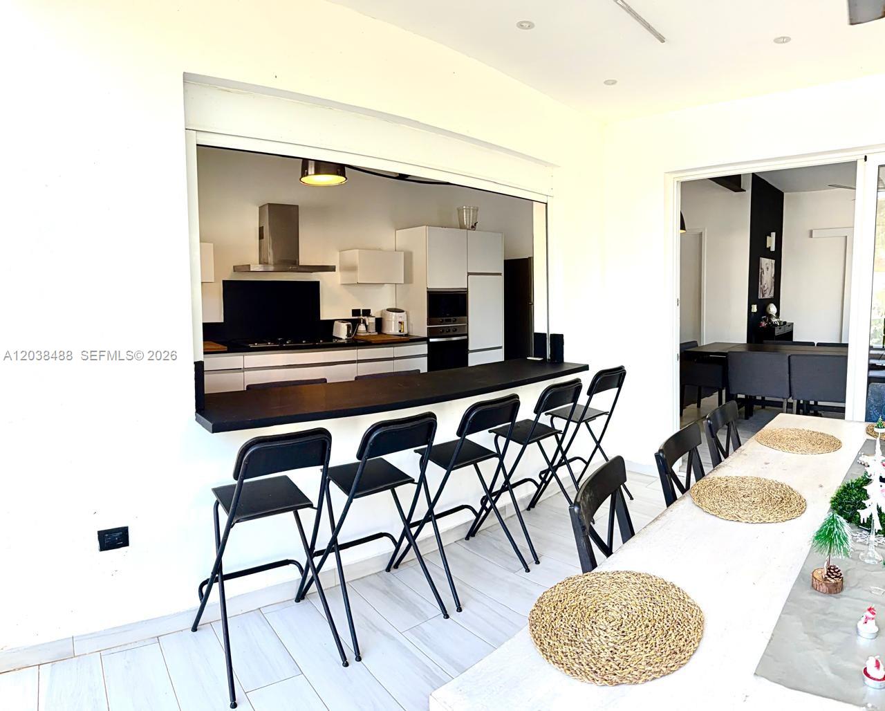 A kitchen with a pass-through window and breakfast bar overlooks a dining area — 00 CALLE MARIANO VANDERHORST, 3200, FL