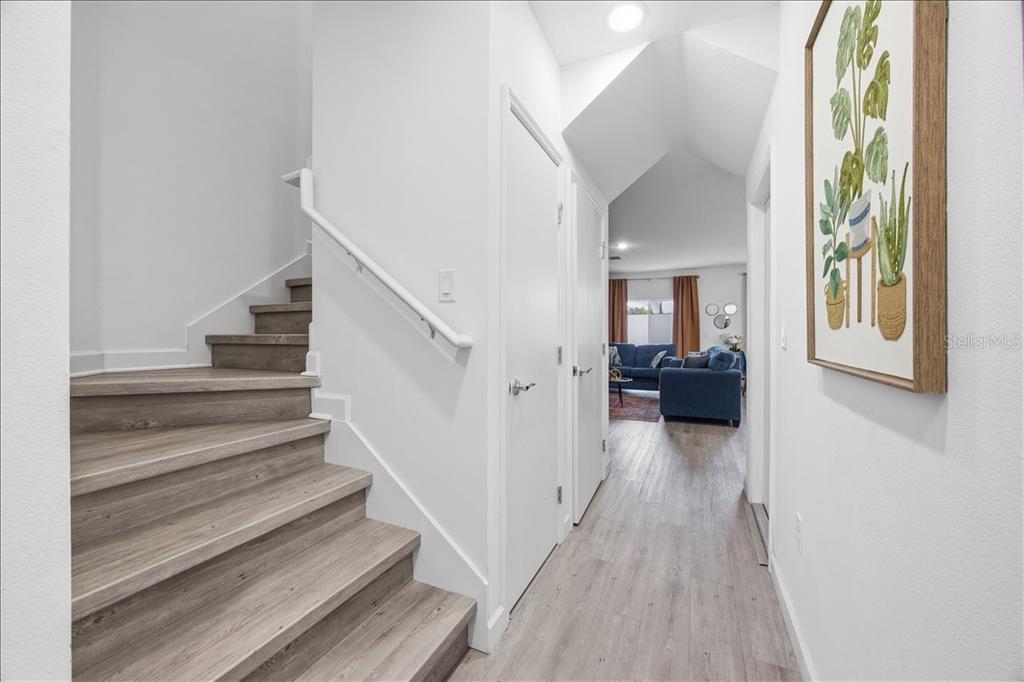 A staircase with wood-look flooring leads upward next to a hallway with white walls — 620 TRIKOMO DRIVE, DAVENPORT, FL
