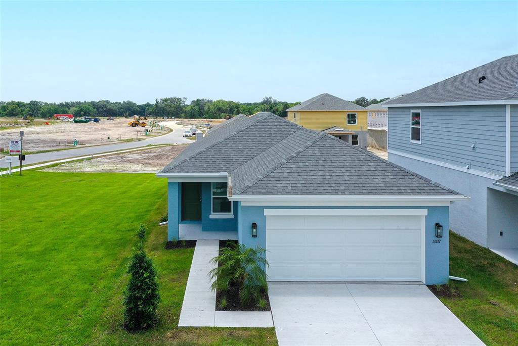 An elevated exterior view of a blue single-story house with a two-car garage — 13004 SASSAFRAS TRAIL, PARRISH, FL