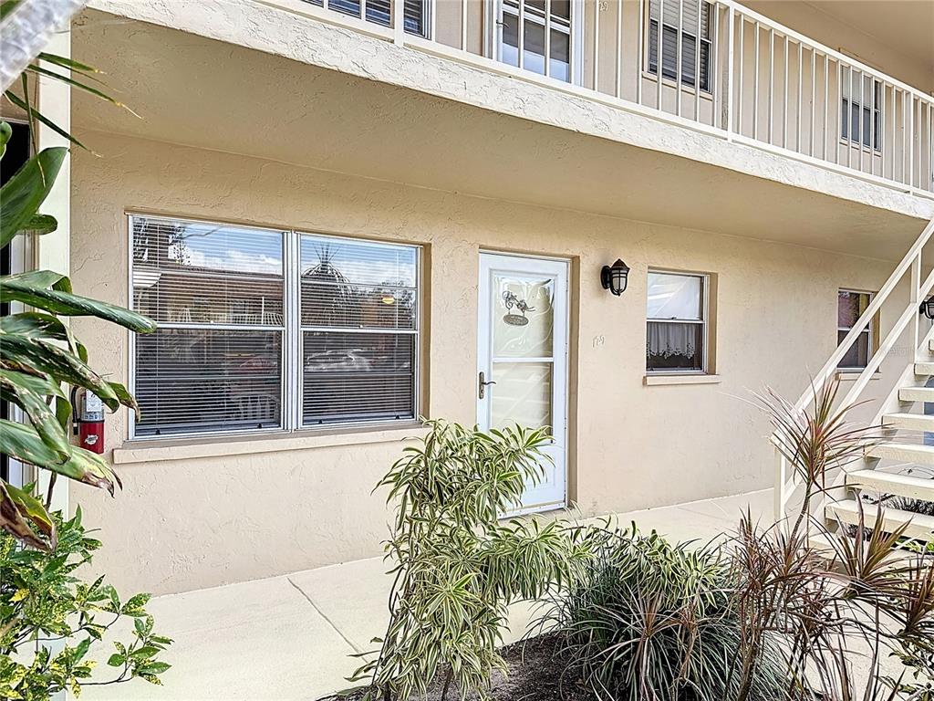 A beige apartment building exterior features a front door, windows, and an outdoor staircase — 210 PARK BOULEVARD N UNIT 129, VENICE, FL