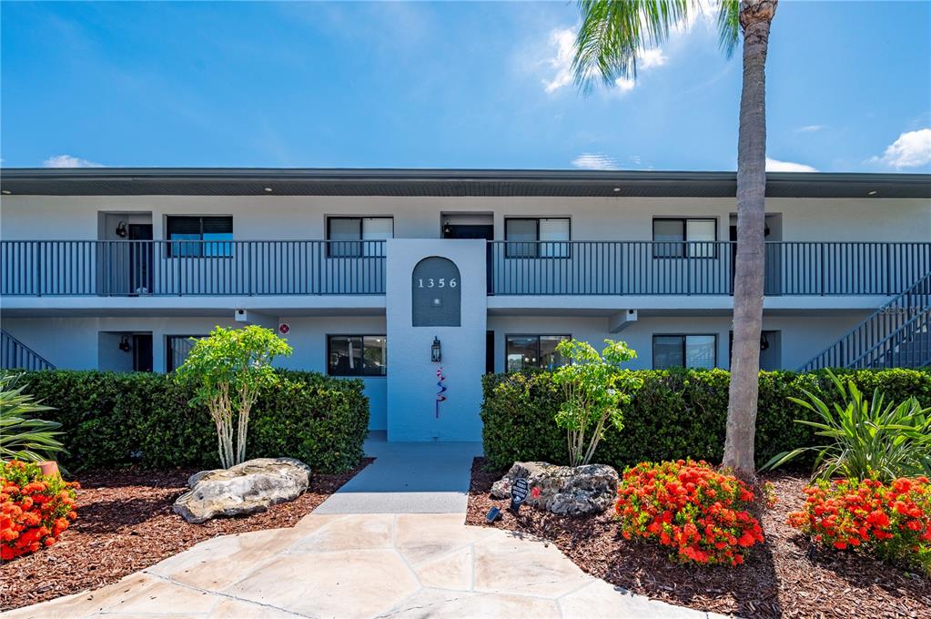 A two-story apartment building exterior features a central entrance with the number 1356 — 1356 RIO DE JANEIRO AVENUE UNIT 108, PUNTA GORDA, FL