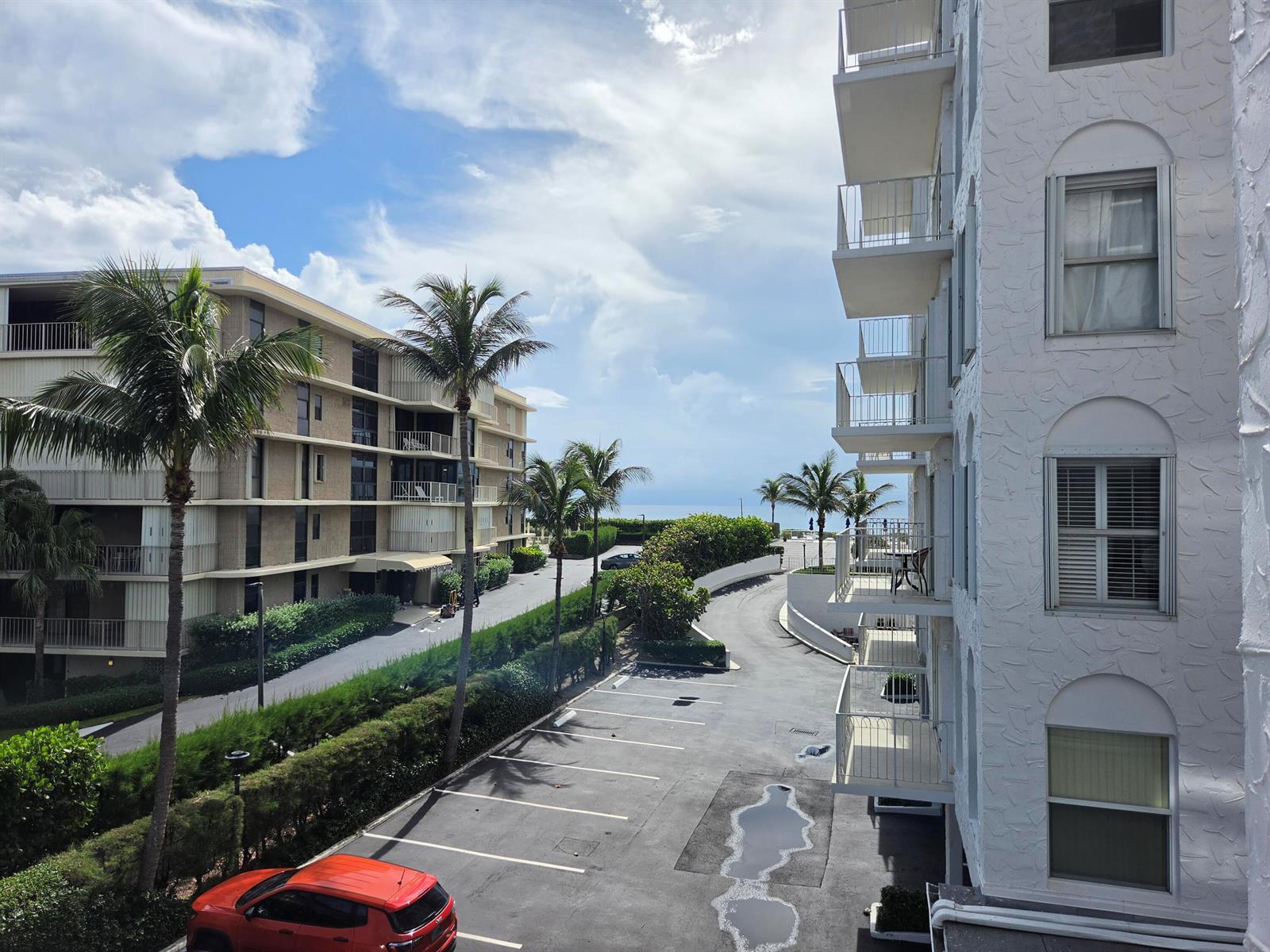An elevated view shows a parking lot between two apartment buildings with palm trees nearby — 3230 S Ocean Boulevard # C205, Palm Beach FL 33480, PALM BEACH, FL