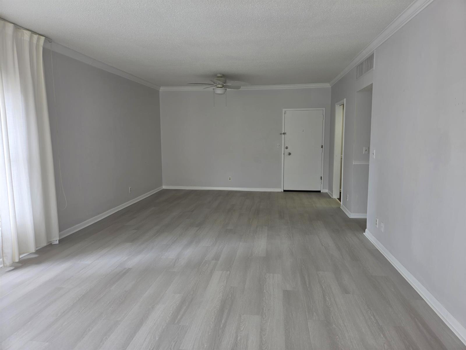 An empty living room features light gray walls, wood-look flooring, and a ceiling fan — 3230 S Ocean Boulevard # C205, Palm Beach FL 33480, PALM BEACH, FL