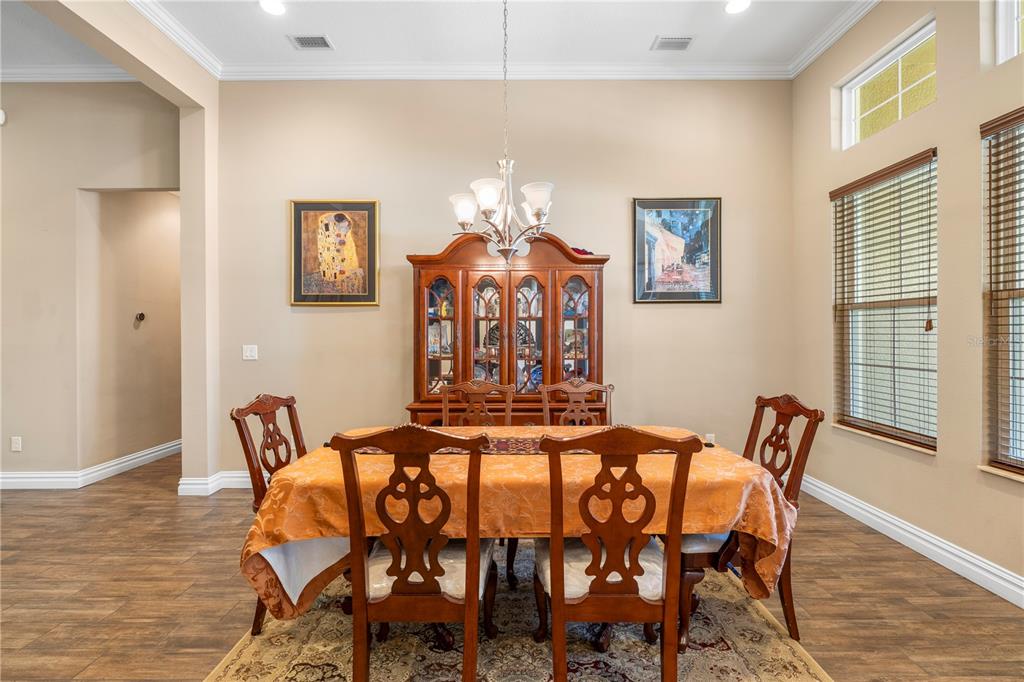 A dining room features a wooden table with chairs, a china cabinet, and wall art — 16726 COURTYARD LOOP, LAND O LAKES, FL