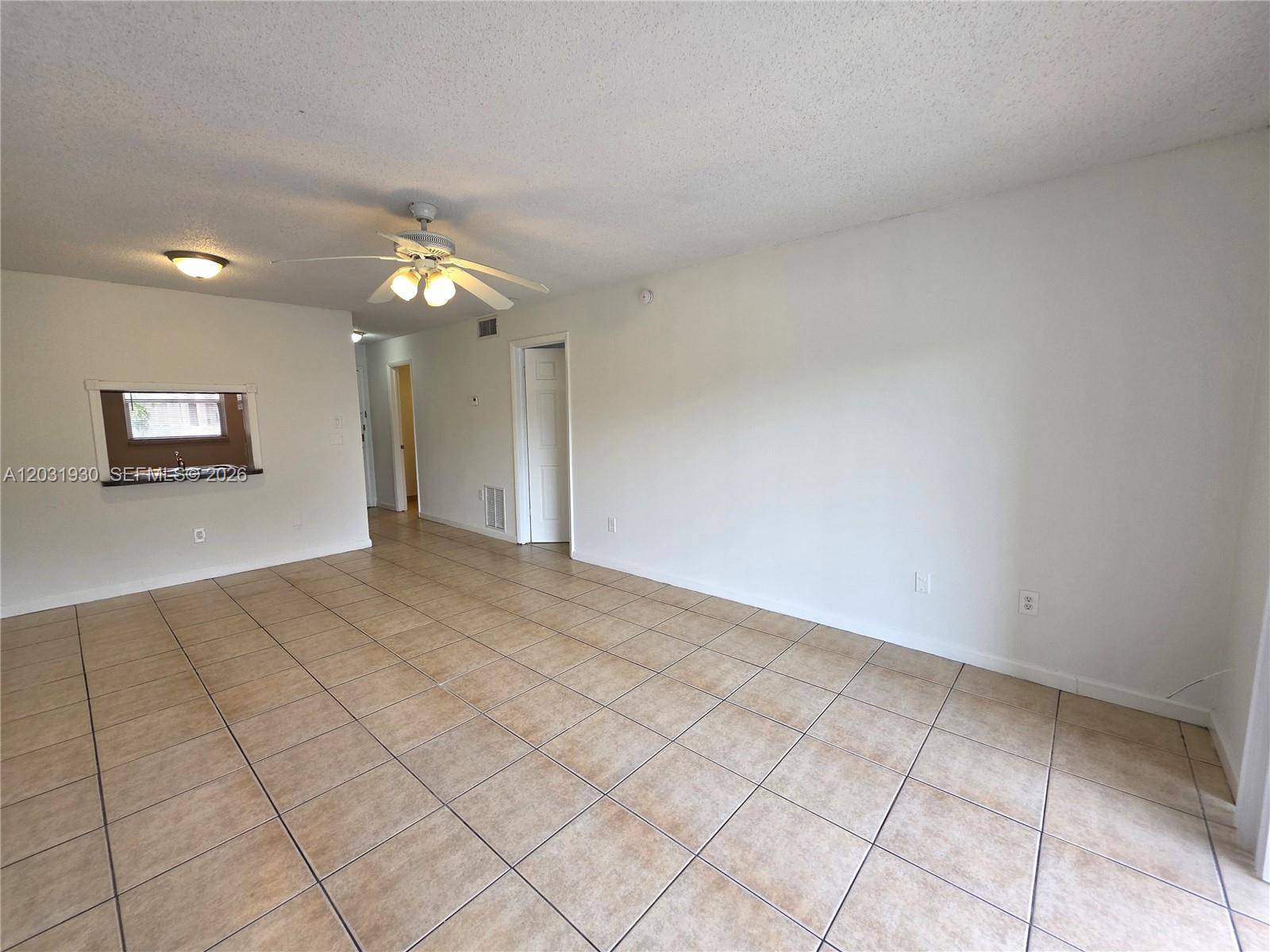 An empty room features beige tile flooring, white walls, and a ceiling fan — 2800 NW 56th Ave # E303, Lauderhill FL 33313, LAUDERHILL, FL