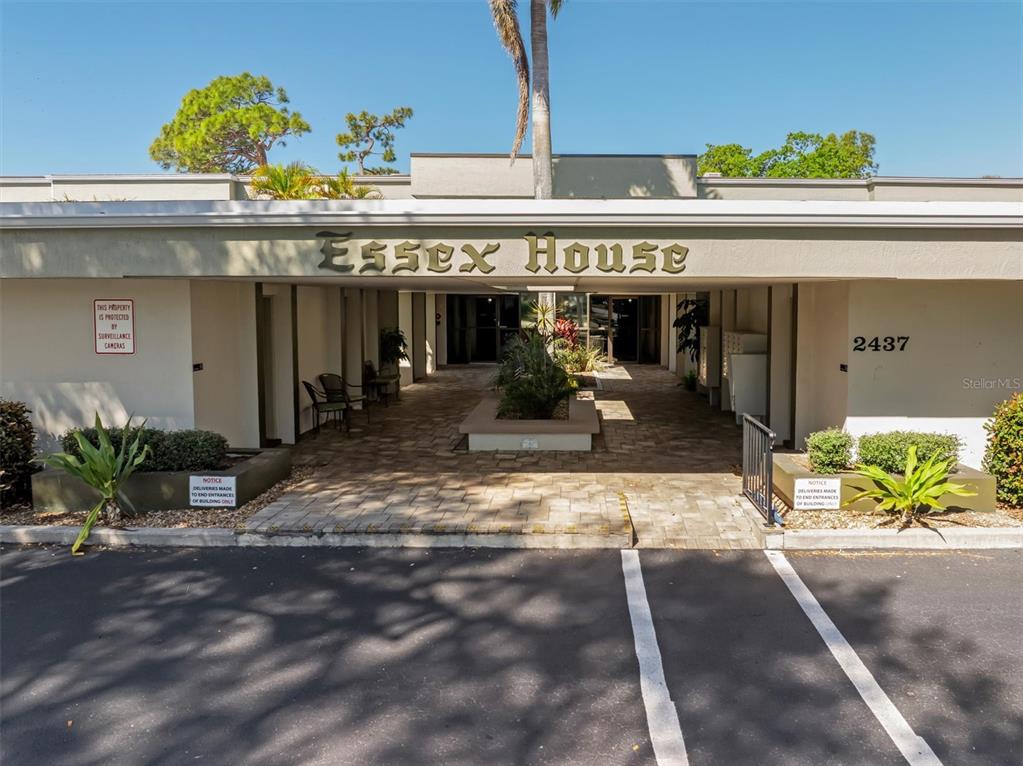 The exterior entrance of a building features a covered walkway with a paved courtyard — 2437 HARBOR BOULEVARD UNIT 204, PORT CHARLOTTE, FL