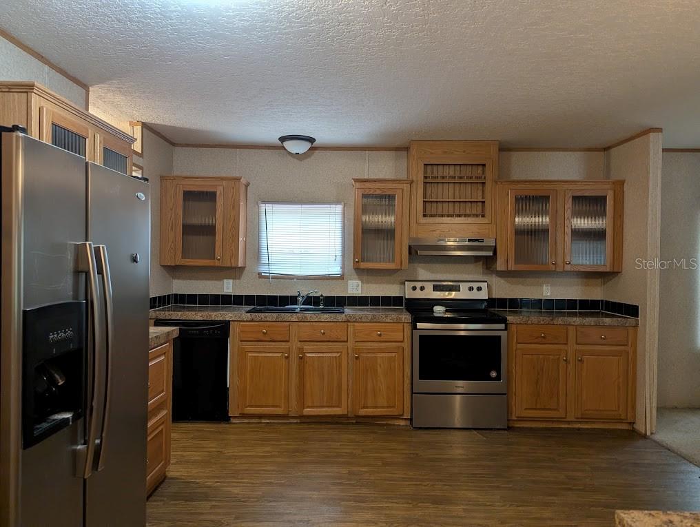 A kitchen with wood cabinets, stainless steel appliances, and dark countertops — 15319 SW 114TH PLACE, ARCHER, FL