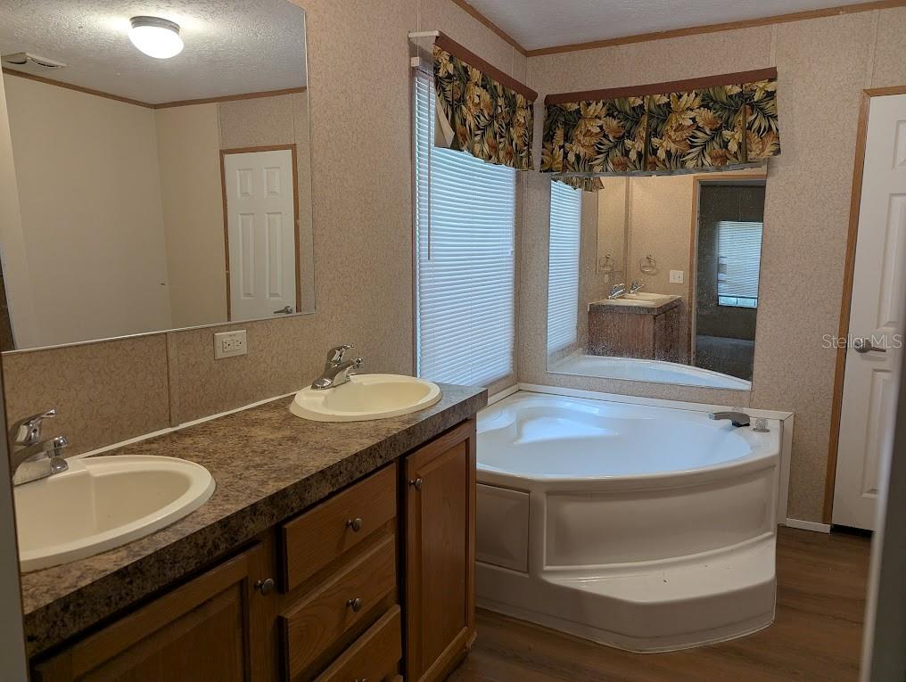 A bathroom features a tiled walk-in shower, a corner soaking tub, and wood-look flooring — 15319 SW 114TH PLACE, ARCHER, FL