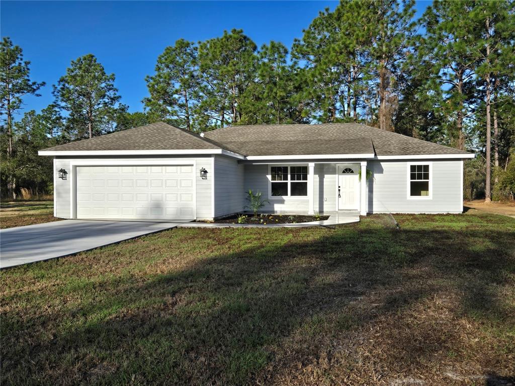 A single-story house with light gray siding, a two-car garage, and a front porch — 2988 SW BONABLE DRIVE, DUNNELLON, FL