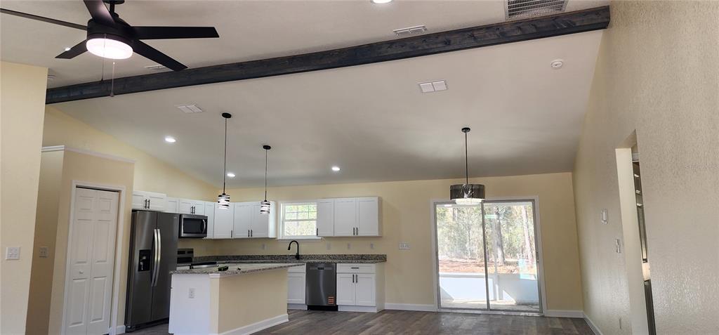 A kitchen with white cabinets, granite countertops, stainless steel appliances, and a vaulted ceiling — 2988 SW BONABLE DRIVE, DUNNELLON, FL