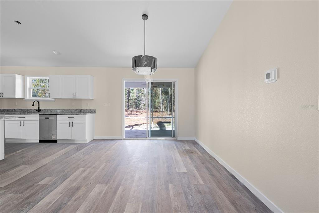 A kitchen and dining area with white cabinets, granite countertops, and a sliding glass door — 2988 SW BONABLE DRIVE, DUNNELLON, FL