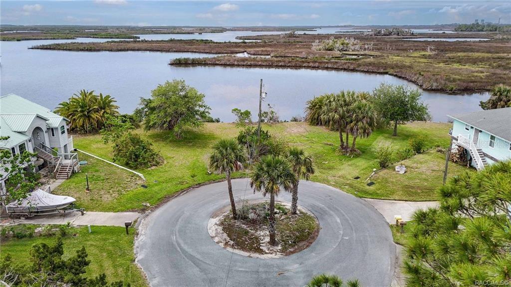 An aerial view shows a circular driveway with palm trees overlooking a coastal marshland — 11889 W COQUINA COURT, CRYSTAL RIVER, FL