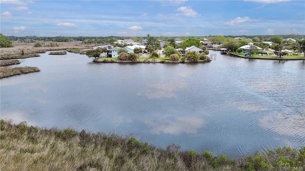 An aerial view shows houses situated on a peninsula surrounded by a calm waterway — 11889 W COQUINA COURT, CRYSTAL RIVER, FL