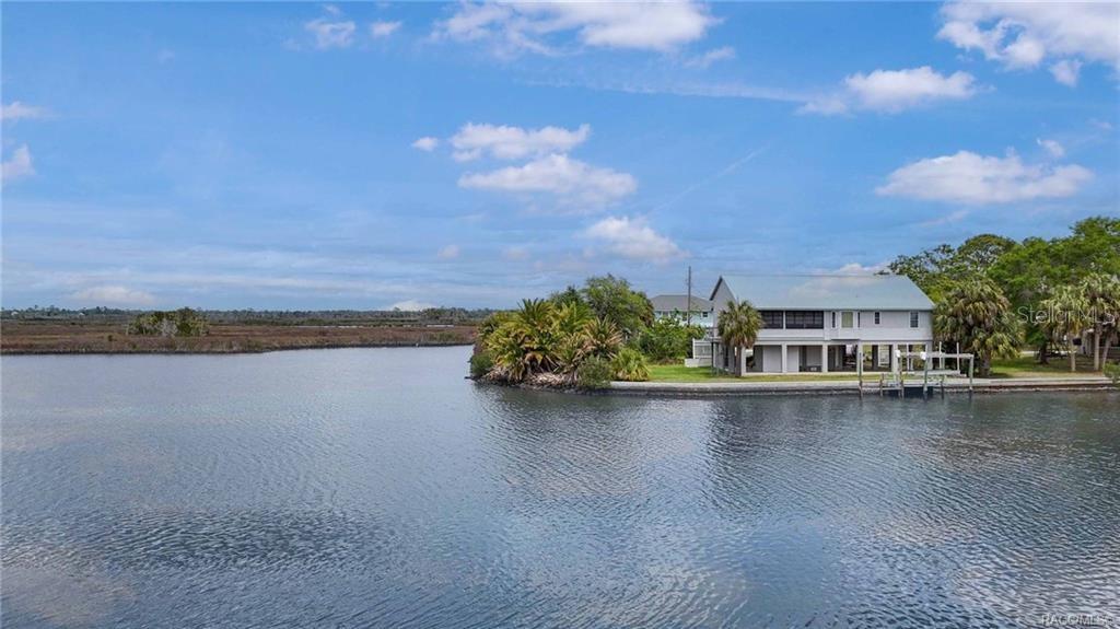 A two-story house with a metal roof sits on a point overlooking a waterway — 11889 W COQUINA COURT, CRYSTAL RIVER, FL