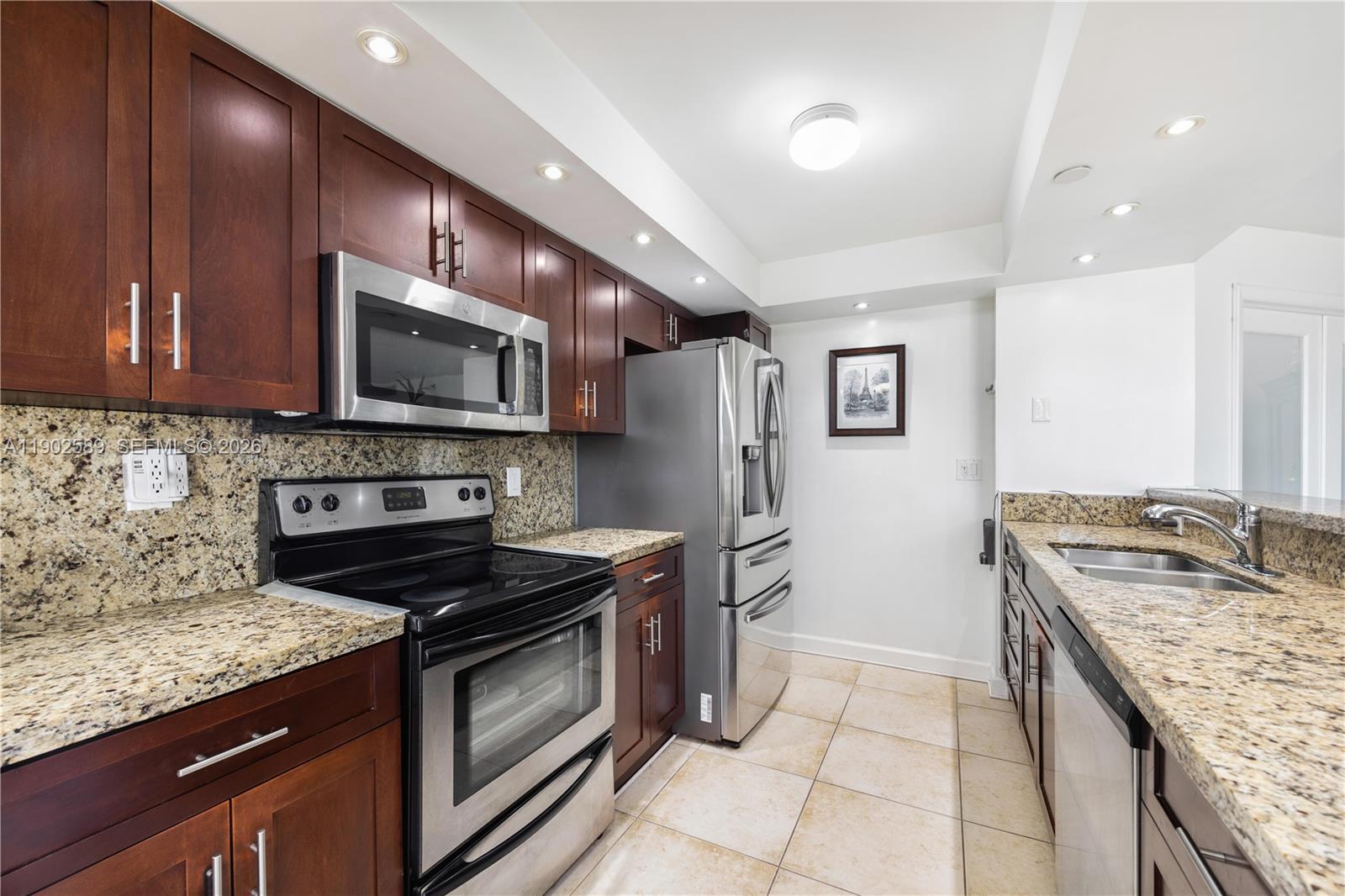 A kitchen features dark wood cabinets, granite countertops, and stainless steel appliances — 4000 Towerside Ter # 412, Miami FL 33138, MIAMI, FL