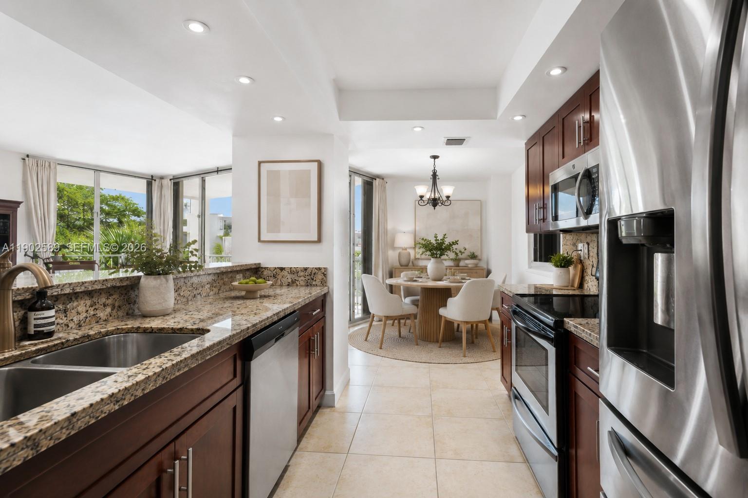 A kitchen with granite countertops and dark wood cabinets opens to a dining area — 4000 Towerside Ter # 412, Miami FL 33138, MIAMI, FL