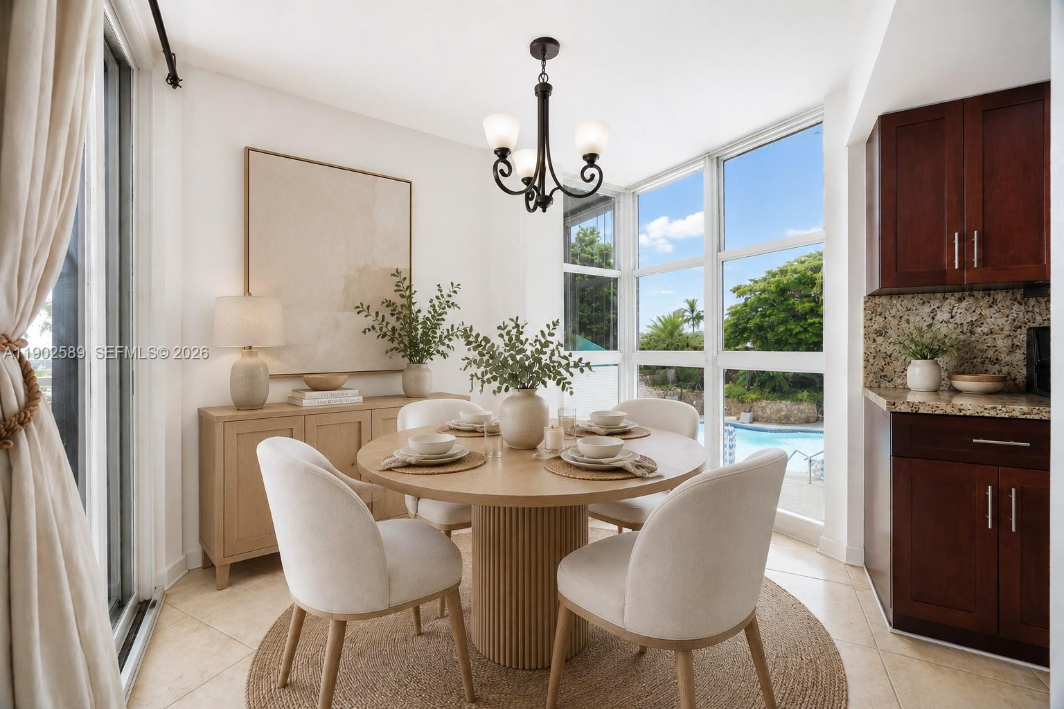 A dining area features a round wooden table, four upholstered chairs, and a view of a pool — 4000 Towerside Ter # 412, Miami FL 33138, MIAMI, FL