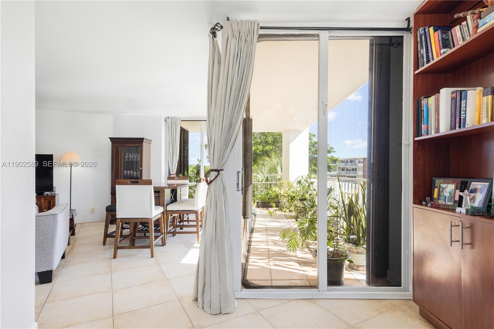 A living and dining area features tile floors, a sliding glass door, and a balcony — 4000 Towerside Ter # 412, Miami FL 33138, MIAMI, FL