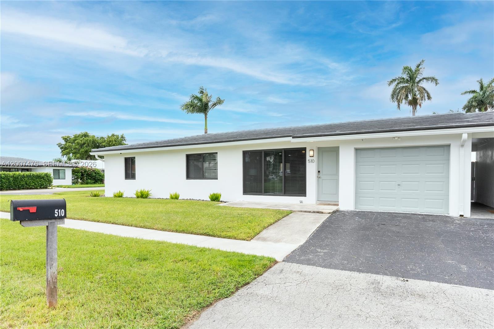 A single-story white house features a gray garage door, a front lawn, and a mailbox — 510 SE 3rd Ave # A, Dania Beach FL 33004, DANIA BEACH, FL