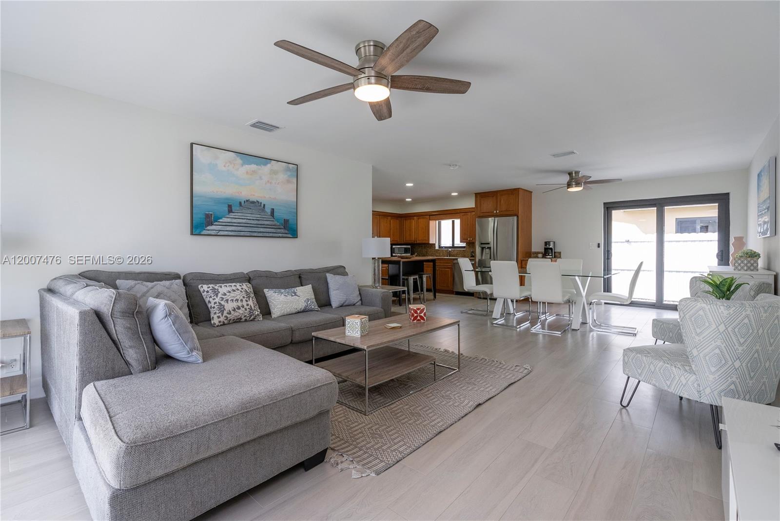 A living and dining area features a gray sectional, wood-look flooring, and an open kitchen — 510 SE 3rd Ave # A, Dania Beach FL 33004, DANIA BEACH, FL