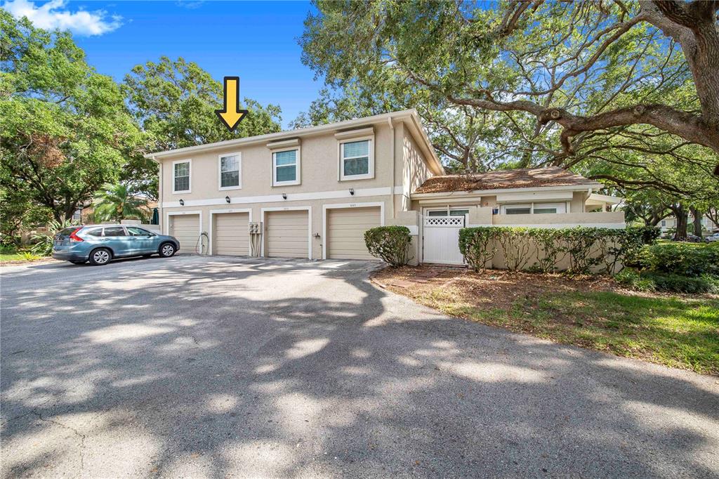 A two-story townhouse exterior features four garage doors, upper-level windows, and a surrounding tree canopy — 11857 NORTHTRAIL AVENUE, TEMPLE TERRACE, FL
