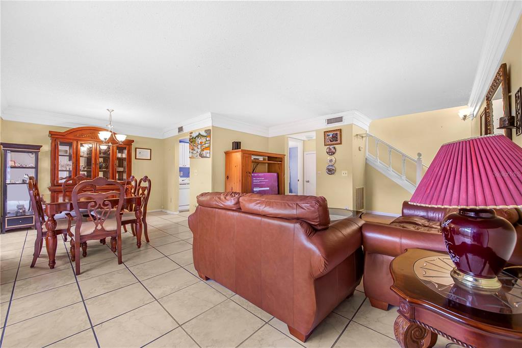 A living and dining area with tile floors, leather furniture, and a staircase — 11857 NORTHTRAIL AVENUE, TEMPLE TERRACE, FL