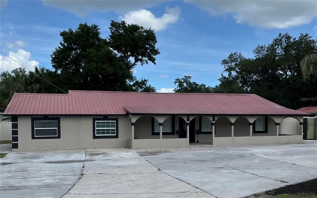 A single-story house with a red metal roof and a concrete driveway in front — 4120 ORANGE AVENUE, MULBERRY, FL