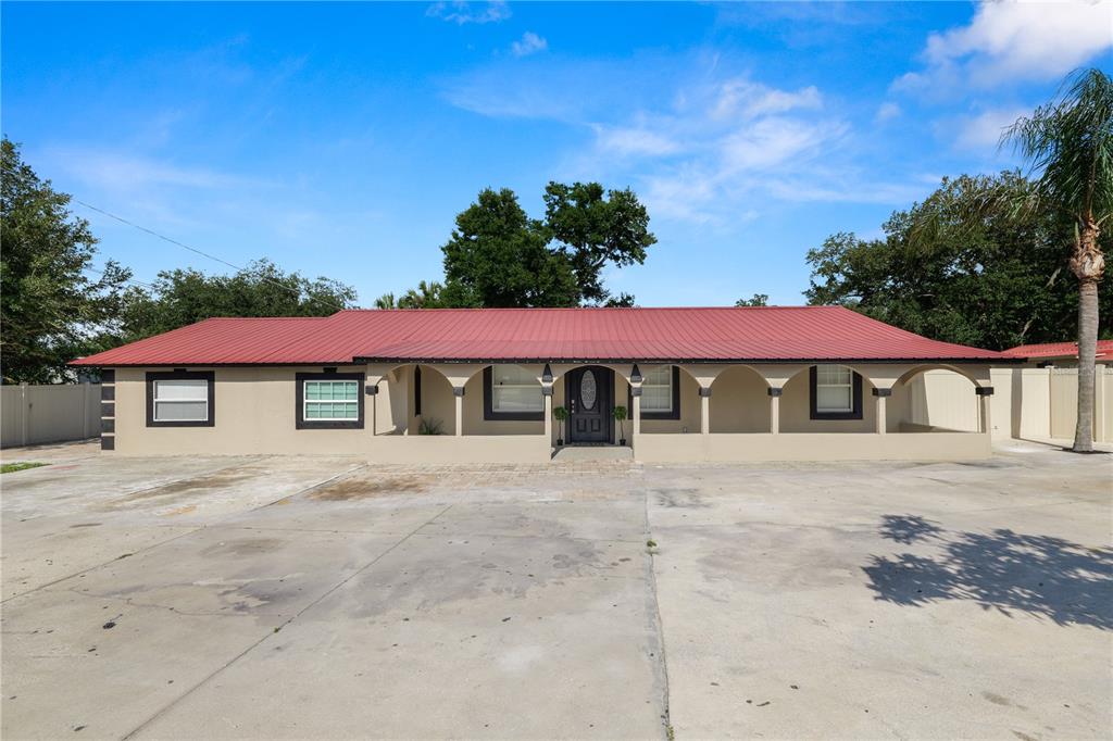 A beige house with a black roof and trim sits behind a black metal gate — 4120 ORANGE AVENUE, MULBERRY, FL