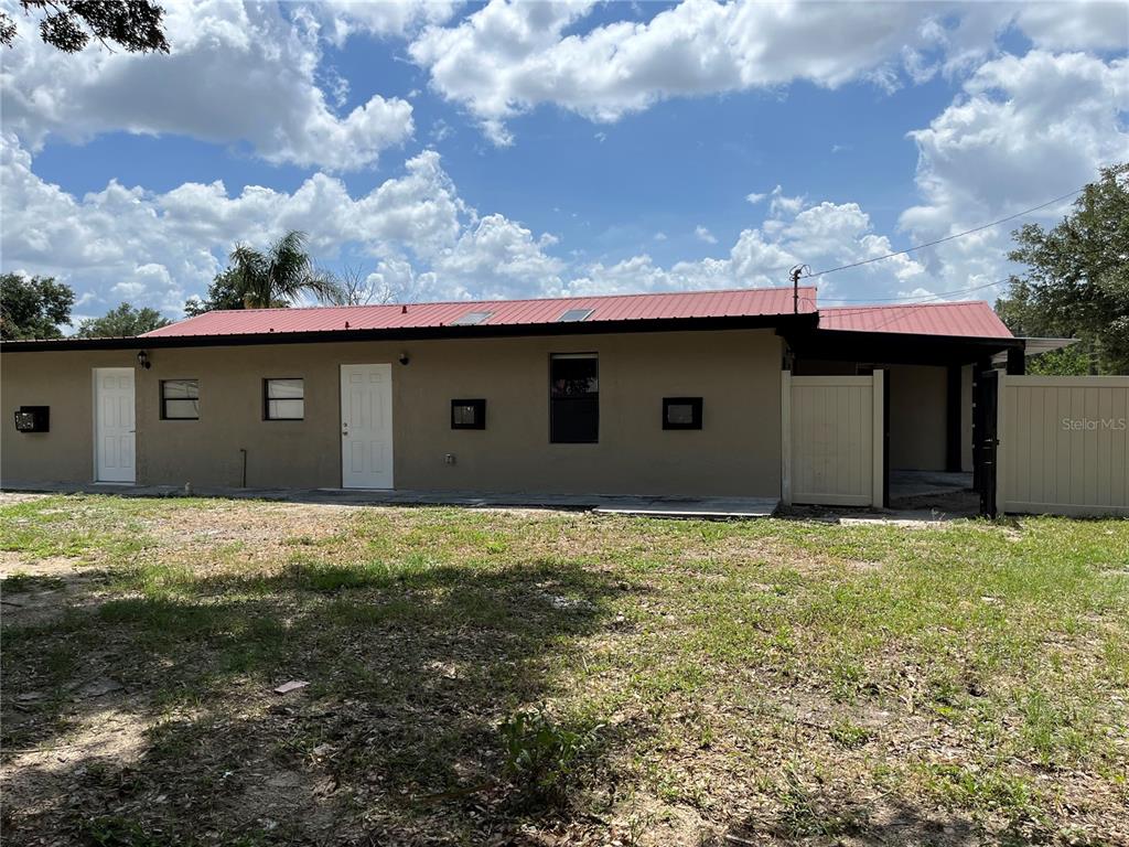 The exterior view shows a beige house with a metal roof and a fenced yard — 4120 ORANGE AVENUE, MULBERRY, FL