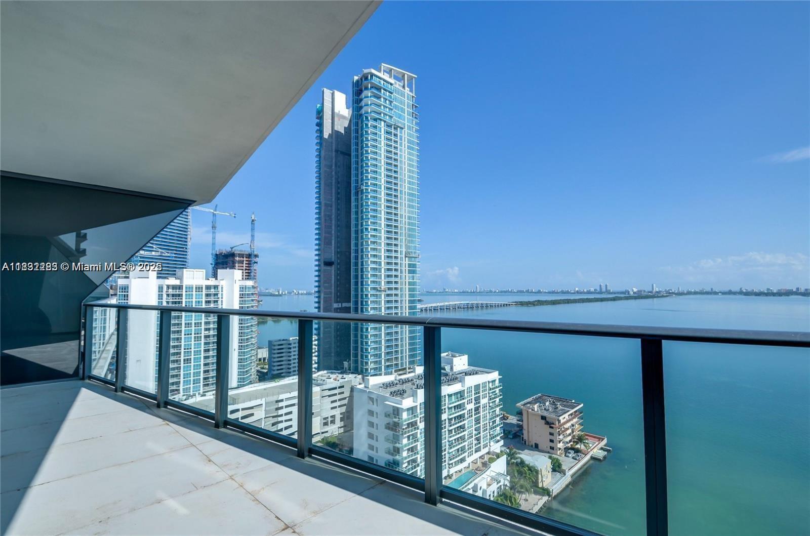 A balcony with a glass railing overlooks a bay, high-rise buildings, and a bridge — 460 NE 28th St # 2106, Miami FL 33137, MIAMI, FL