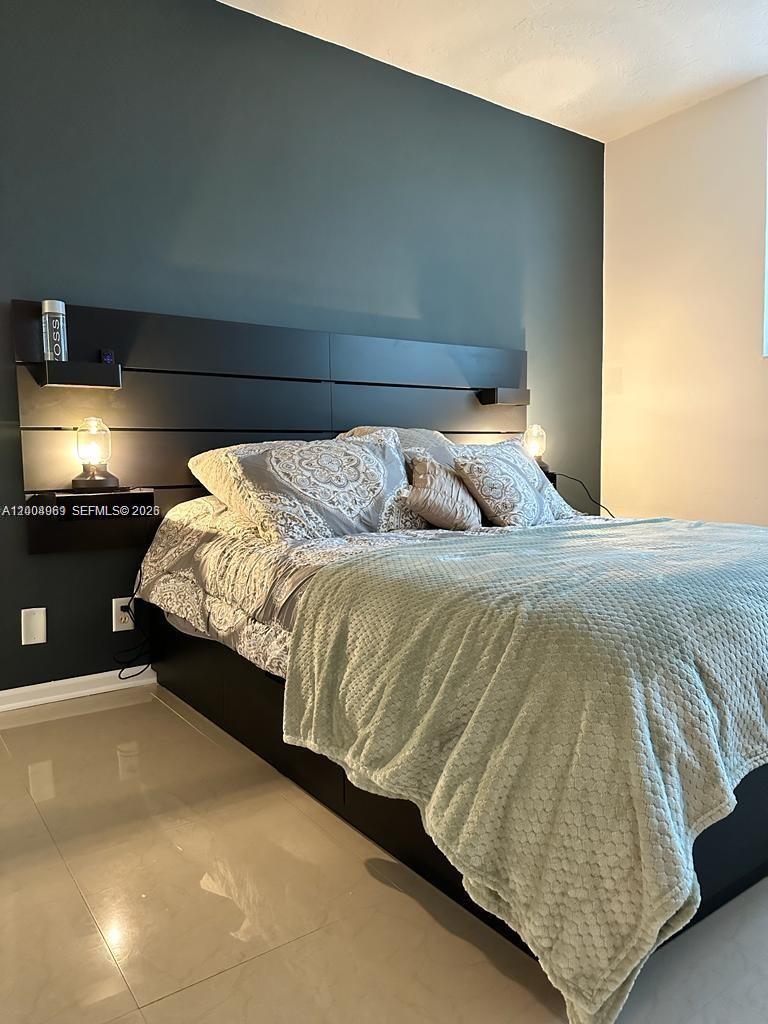 A bedroom features a dark accent wall, a black headboard with built-in lights, and tile flooring — 3000 S Ocean Dr # 414, Hollywood FL 33019, HOLLYWOOD, FL