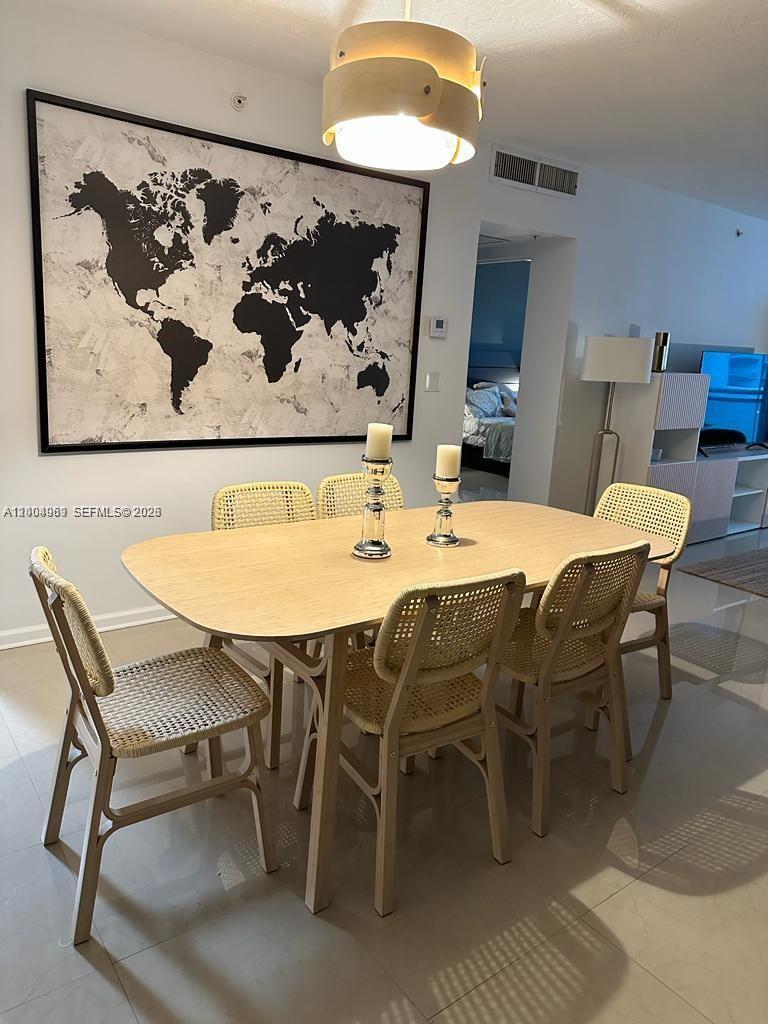 A dining room features a light wood table, six cane chairs, and a world map artwork — 3000 S Ocean Dr # 414, Hollywood FL 33019, HOLLYWOOD, FL