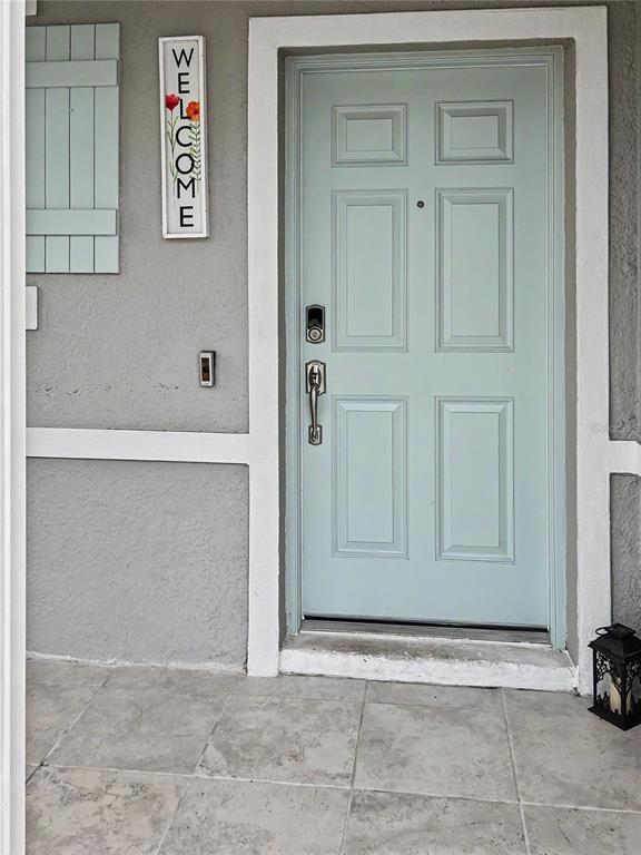 A light blue front door with a smart lock sits on a gray porch — 2239 CANYON BREEZE AVENUE, KISSIMMEE, FL