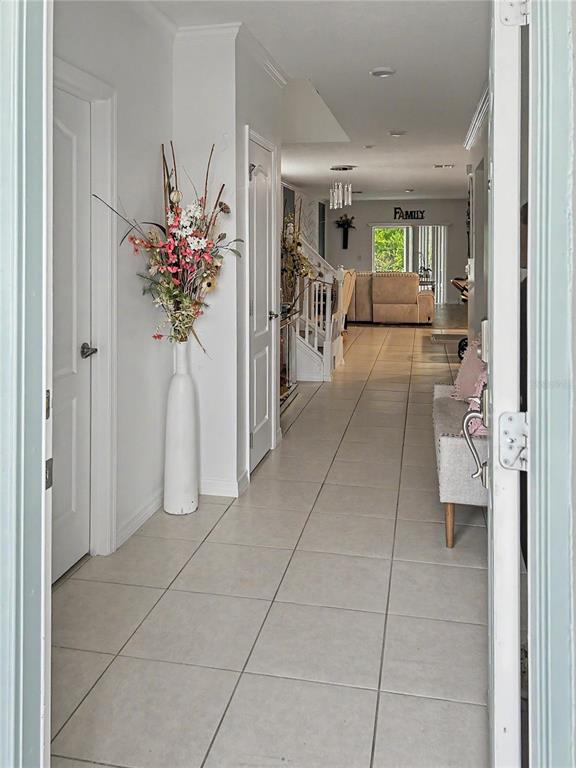 A tiled entryway leads into a home with a staircase and a distant living area — 2239 CANYON BREEZE AVENUE, KISSIMMEE, FL